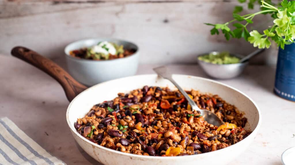Turkey chilli con carne in a white pan that has a wooden handle.