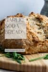 pinterest image for soda bread. A close up of the loaf on a wooden chopping board.