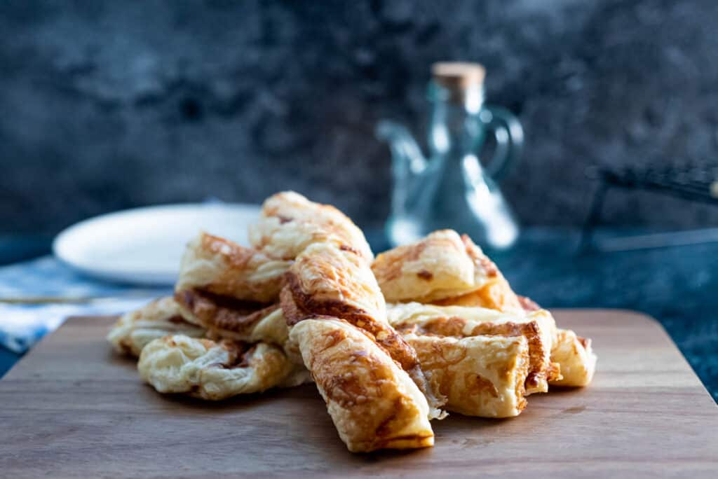 A pile of cheese and Marmite twists on a wooden board.