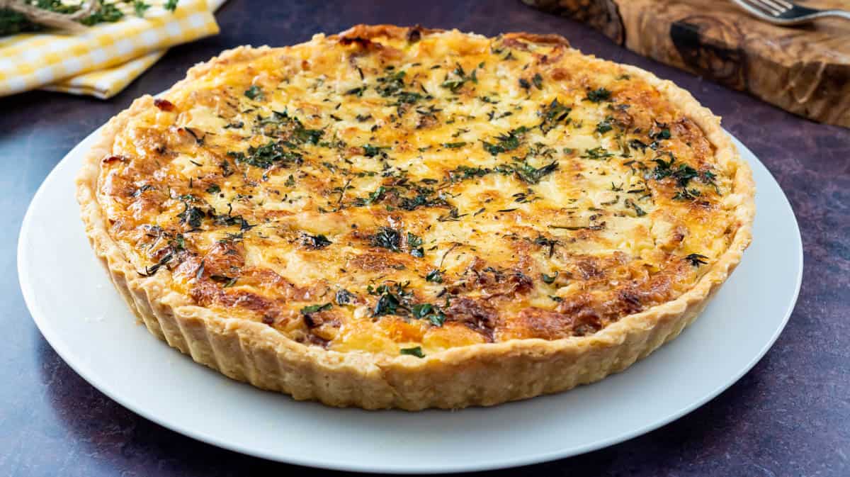 The whole leek and squash quiche on top of a white plate.