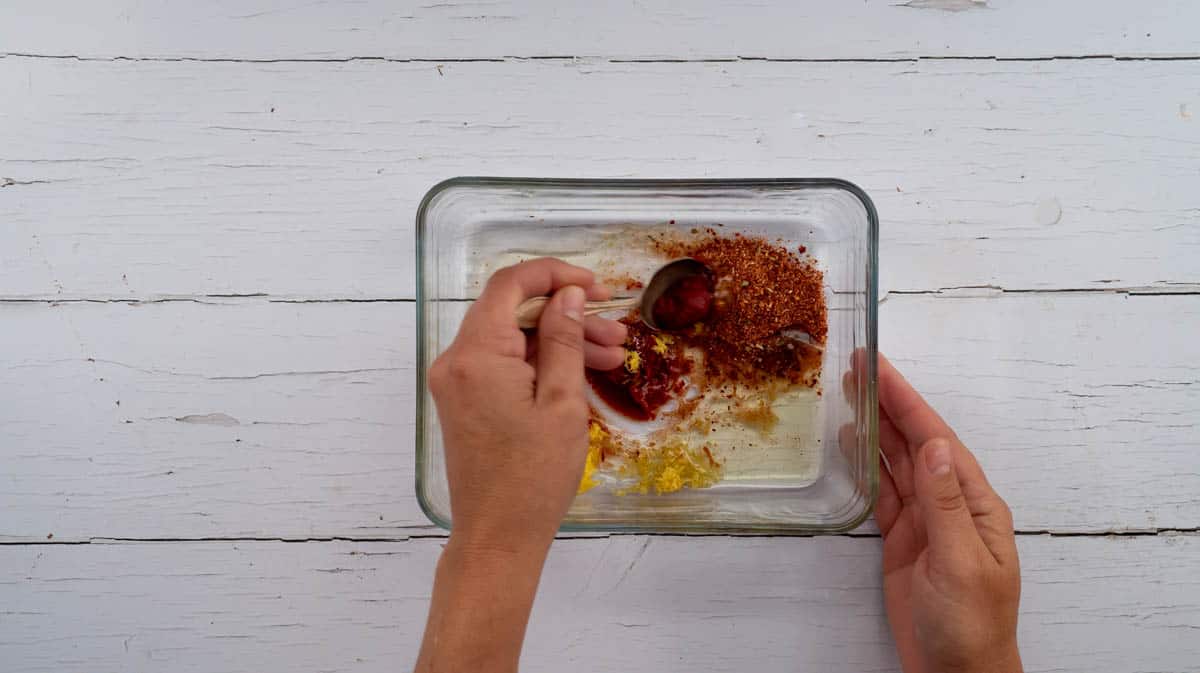 A hand stirring the marinade ingredients together.