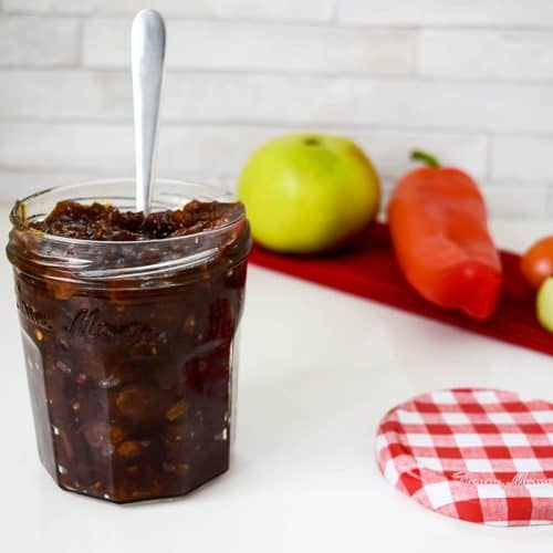 Autumn chutney in a jar with a spoon sticking out of it.