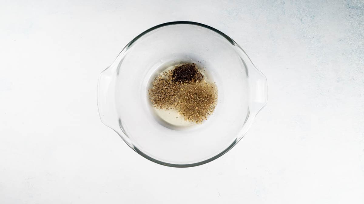 A glass bowl with oil and seasoning inside it.