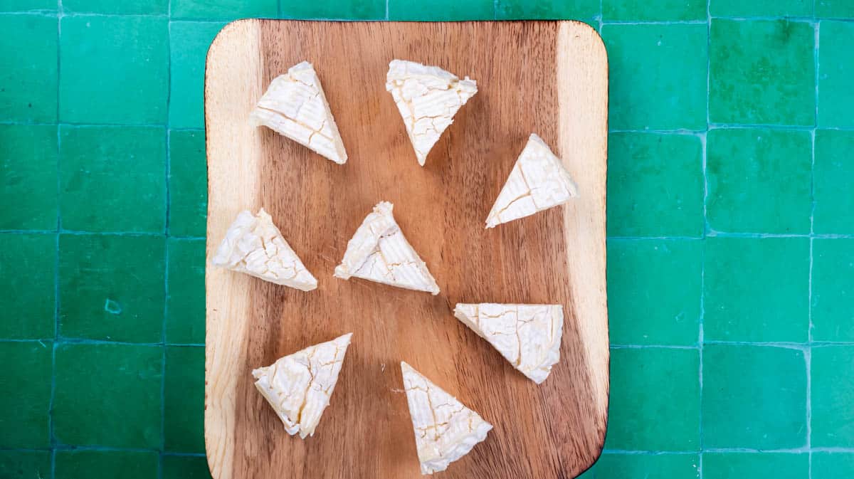 A wooden board with camembert cutting to wedges on top.