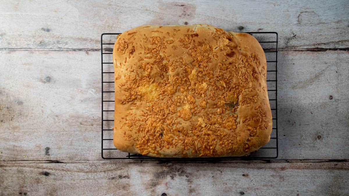 A baked cheese and Marmite loaf on top of a wire cooling rack.