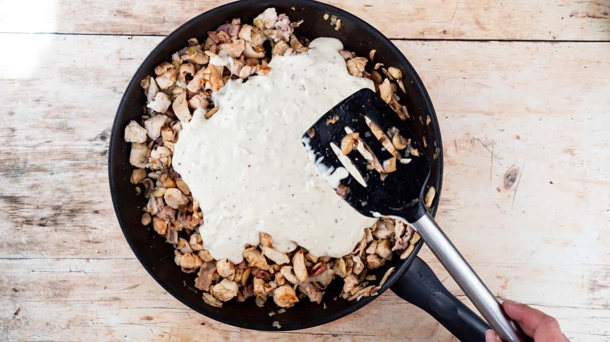 A frying pan containing all the filling ingredients before they are mixed together to make a creamy sauce.