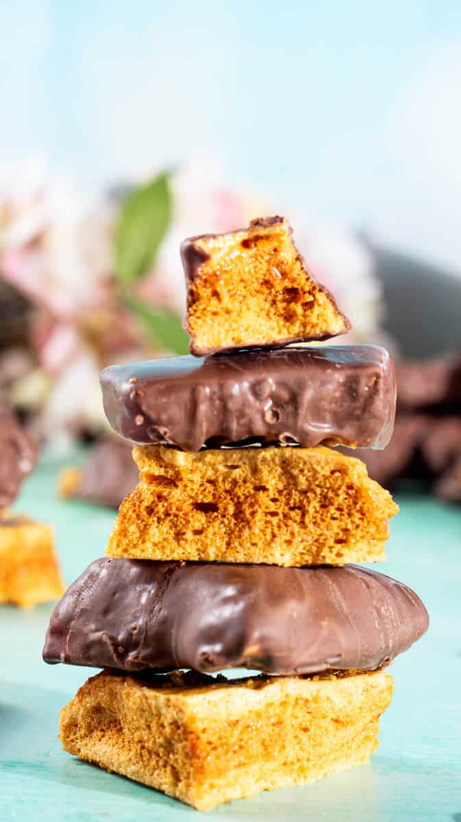 A stack of cinder toffee, some coated in chocolate and others left bare.