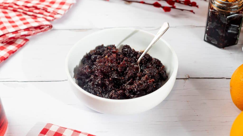 A front view of Cranberry sauce in a white bowl, surrounded by decorative items.