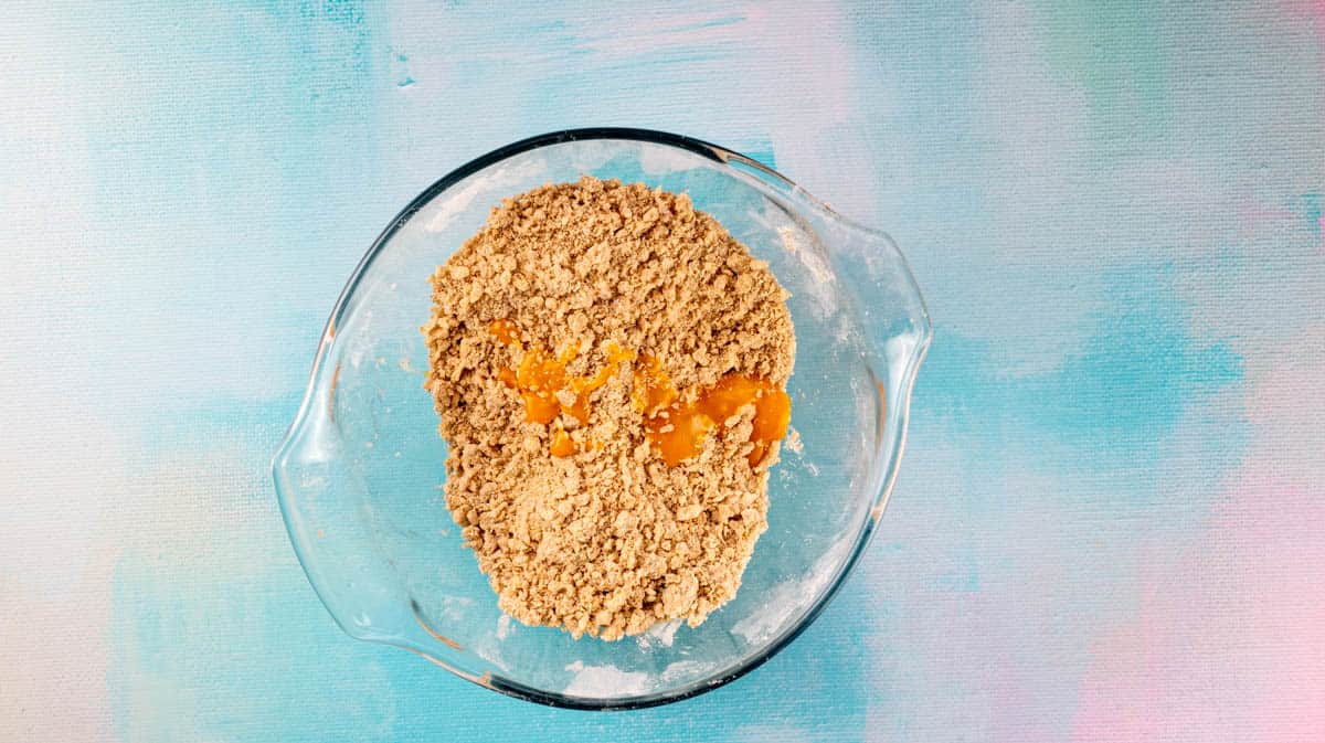 A glass bowl with the dough ingredients inside and an egg yolk added.