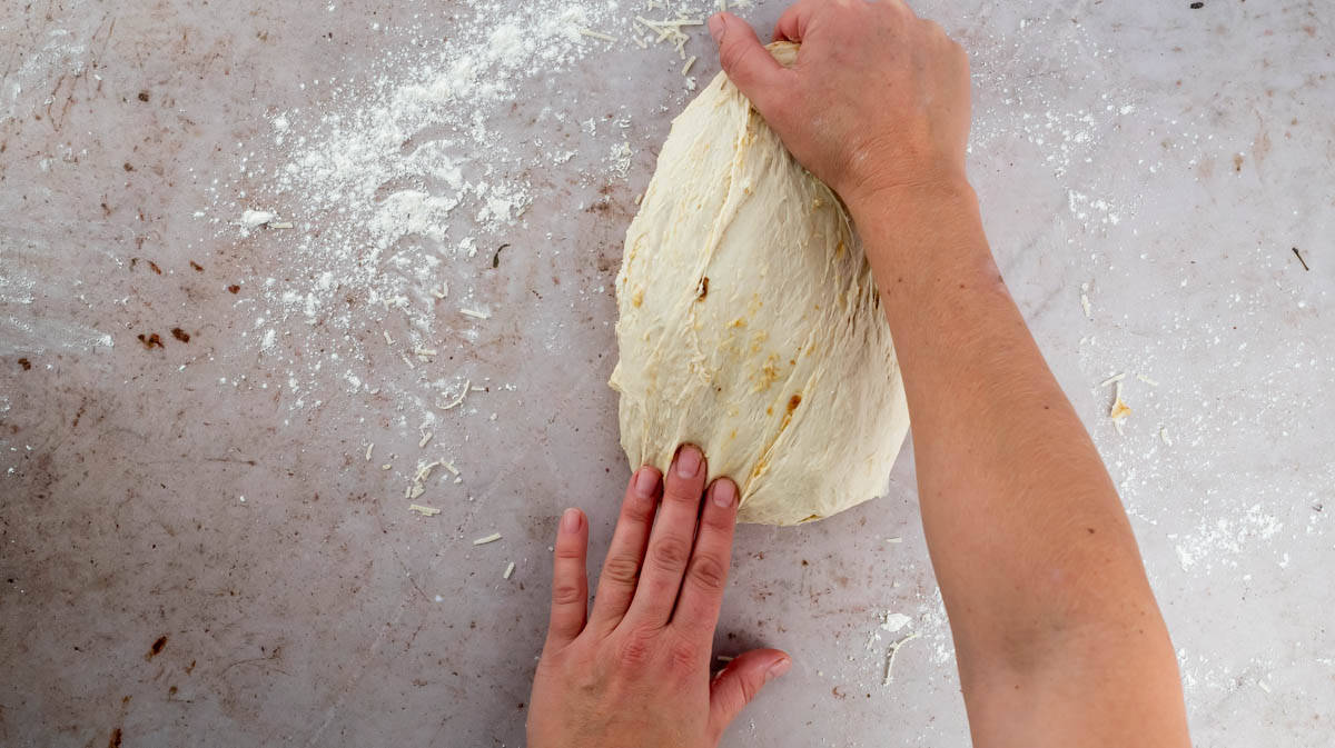 Two hands are kneading the dough again to mix in the flavourings.