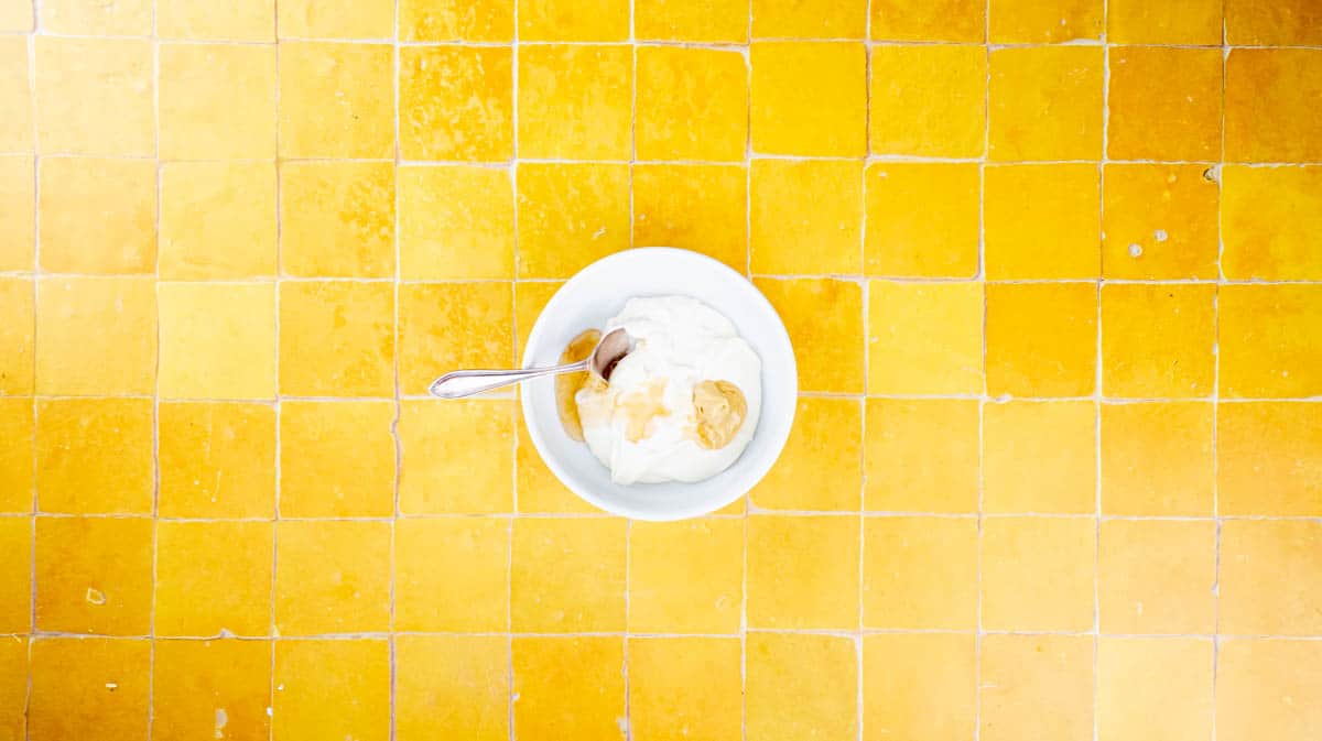 A white bowl with mayonnaise, mustard honey and a spoon inside.