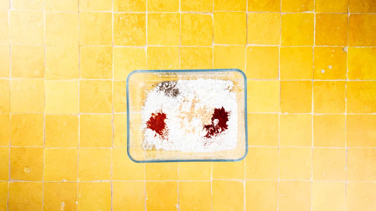 A glass dish with all the ingredients for the flour coating inside before being mixed.