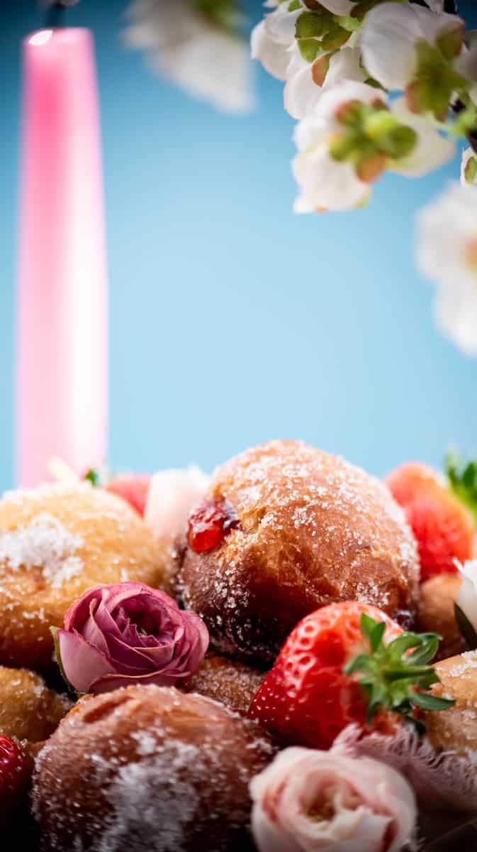 A close up of a jam doughnut on the top of a pile of them.