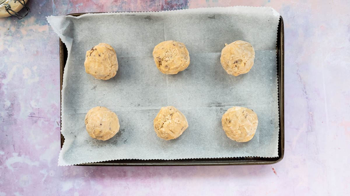 Frozen cookie balls on a hot baking tray ready for baking.
