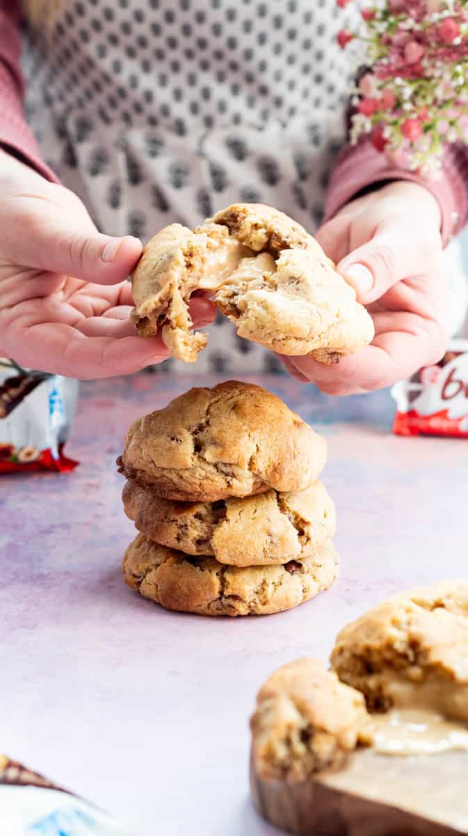 A person is breaking open a Kinder Bueno Cookie to reveal the molten centre.