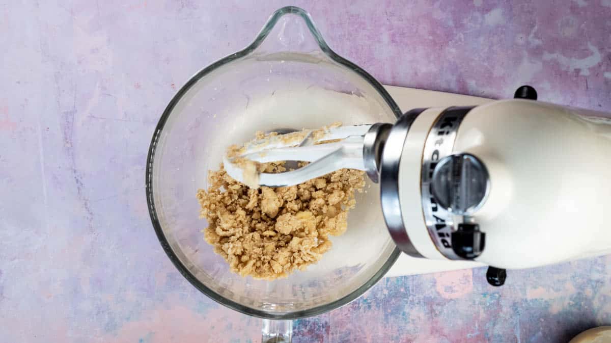 A stand mixer with a glass bowl filled with creamed sugar and butter.