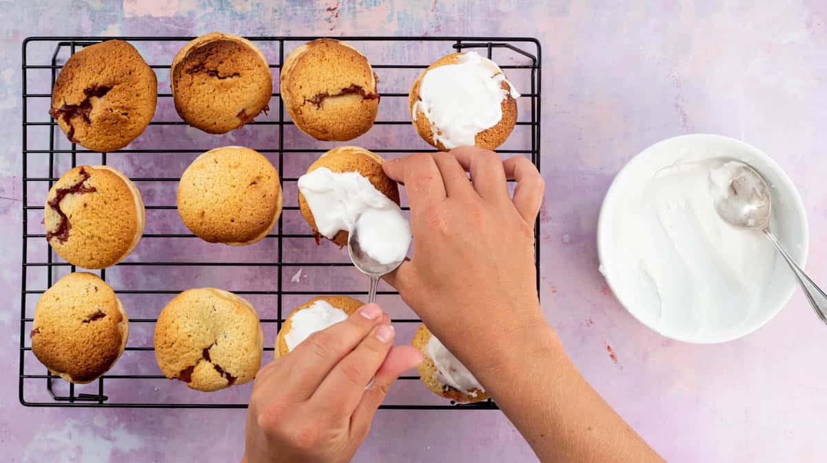 Two hands are spooning icing sugar onto the top of each London Cheesecake.