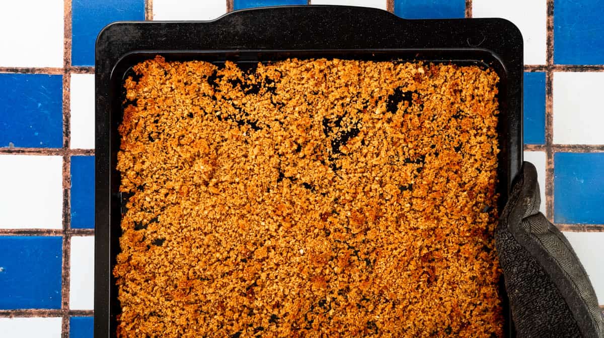 A baking tray filled with a layer of toasted Marmite breadcrumbs.