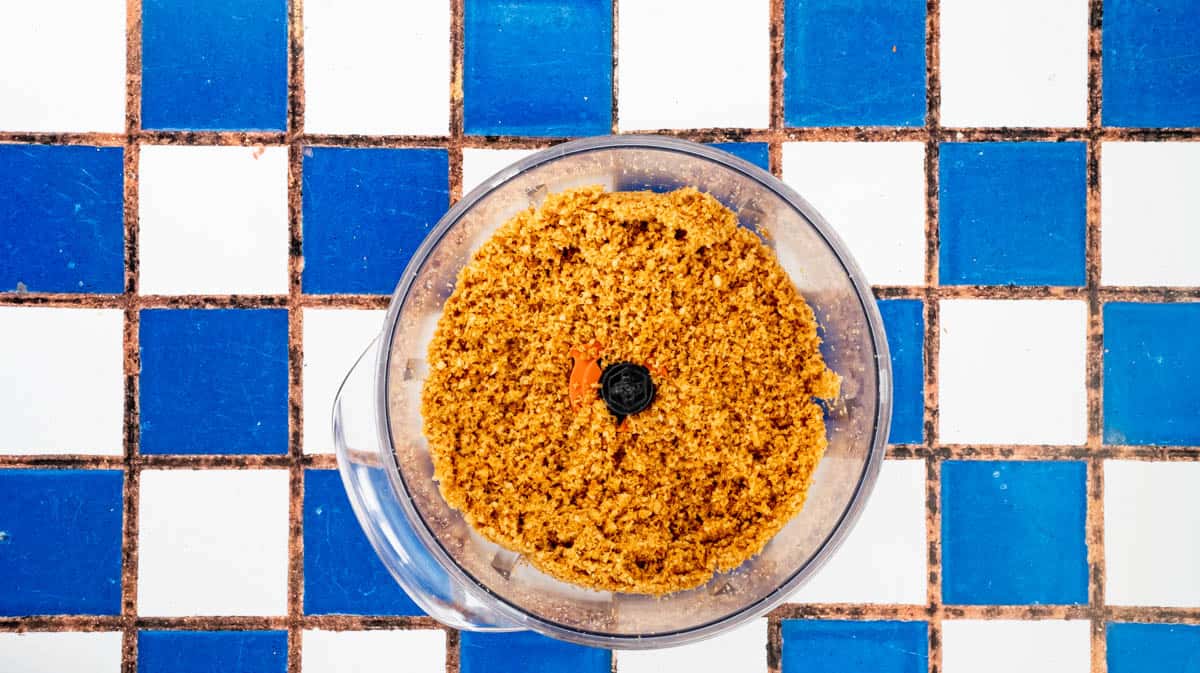 A food processor filled with breadcrumbs that have been coated in Marmite.