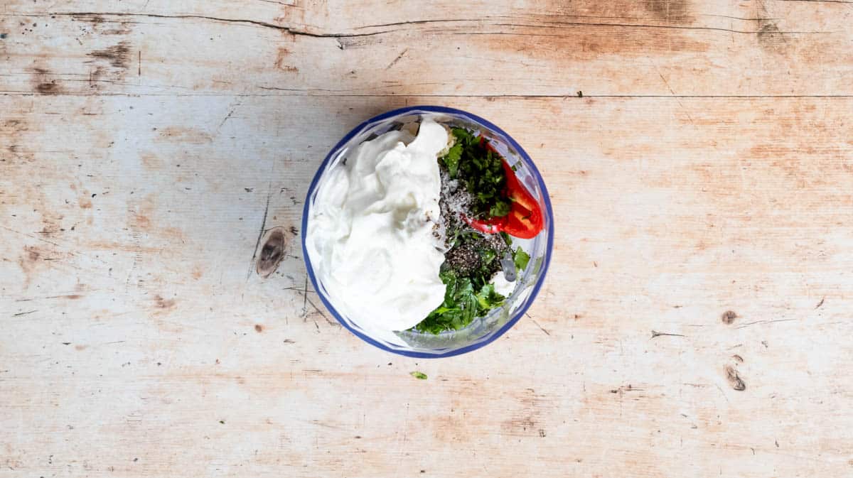 The bowl of a food processor filled with the marinade ingredients before being blended together.