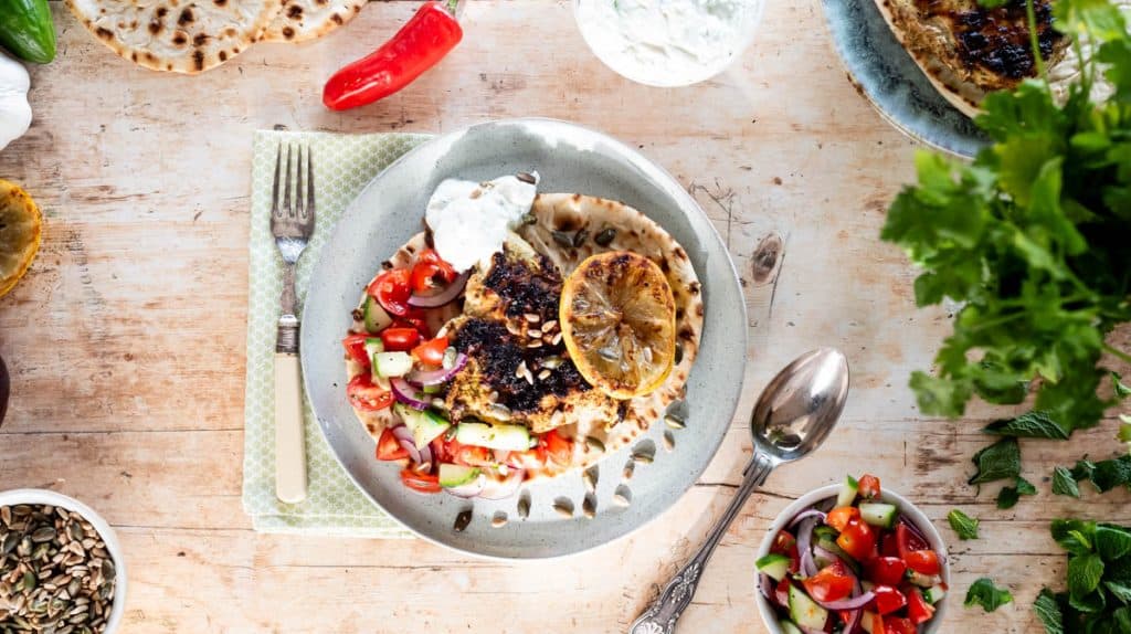 A plate with the open wrap and all ingredients on it. With more components of the dish in bowls around the plate and other ingredients.