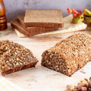 A nut roast log with half of it sliced and the other half whole, surrounded by ingredients and decorative items.