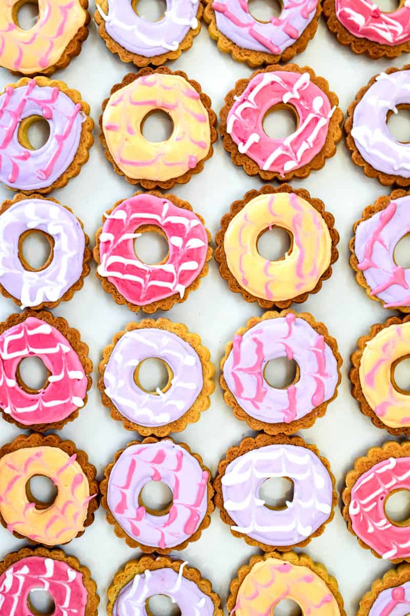 Different coloured party rings biscuits laid down in lines on a white background.