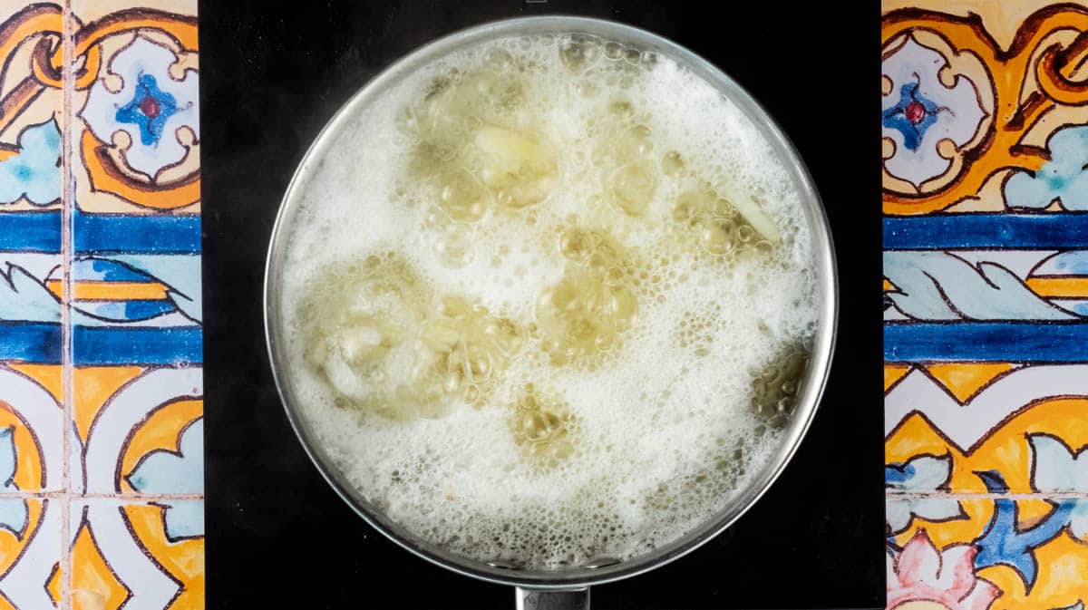 A saucepan with sliced potatoes and water boiling.
