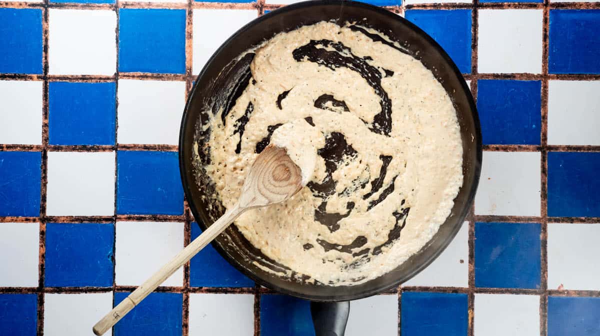 A frying pan which smoked salmon pasta sauce and a wooden spoon sat inside.