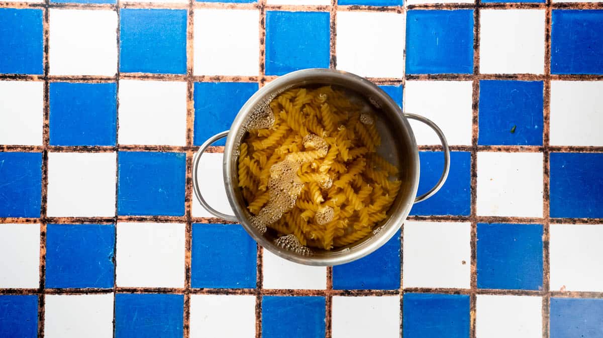 A saucepan filled with water and dried pasta.