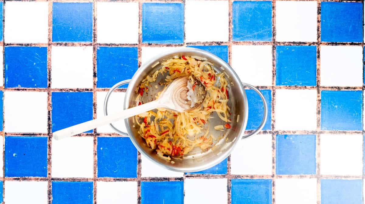A saucepan with cooked onions, garlic and chilli inside.