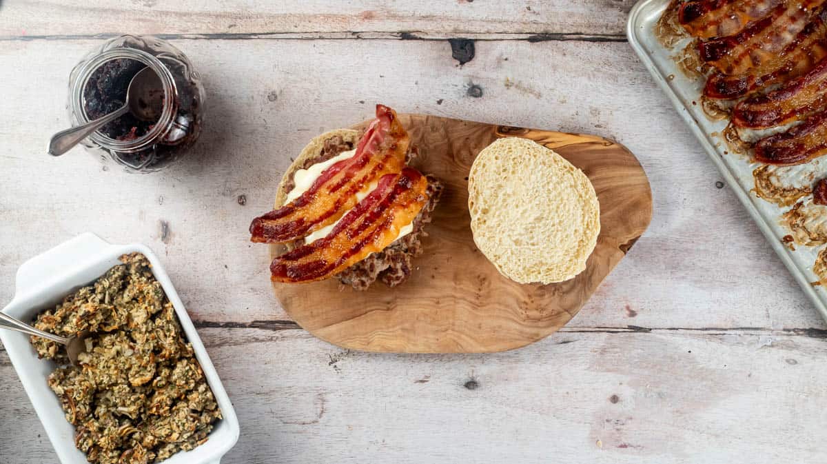 An overhead view of an open burger with the burger patty, melted brie and bacon layered inside it.