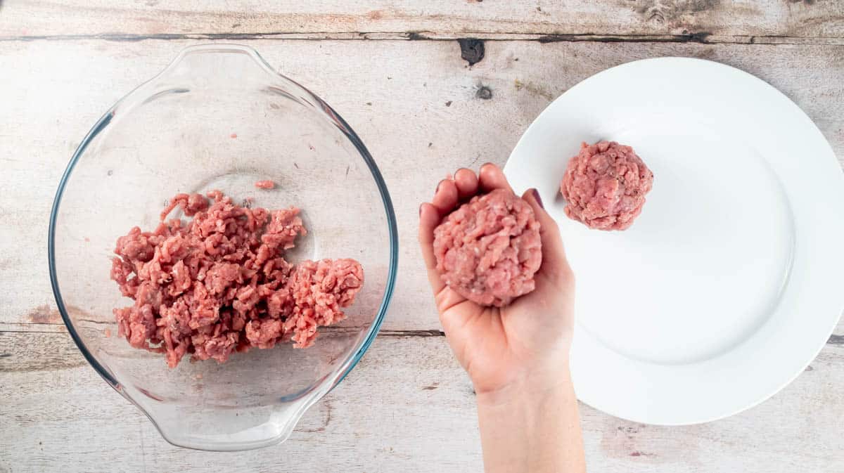 A hand holding a turkey mince ball to show the size.
